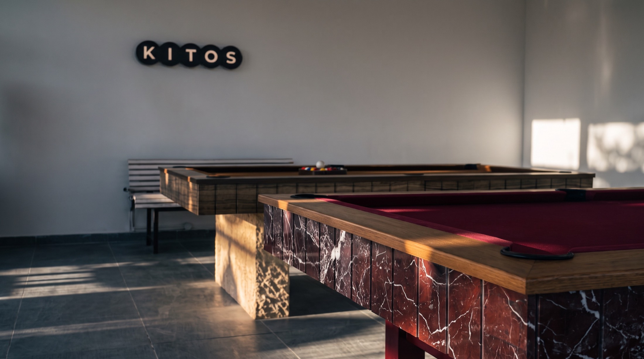 A Rosso Levanto table with an oak rail in the Kitos showroom, the KITOS wall sign behind it